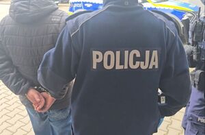Policjanci z zatrzymanym mężczyzną w kajdankach