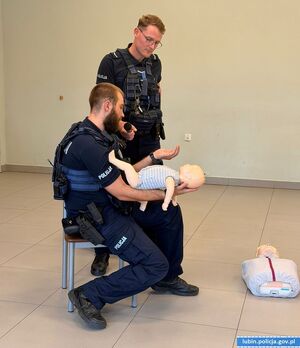 policjant pokazujący pierwszą pomoc na fantomie
