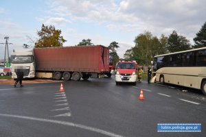 Zdarzenie drogowe na skrzyżowaniu. Samochód ciężarowy, autobus i wóz strażacki w tle