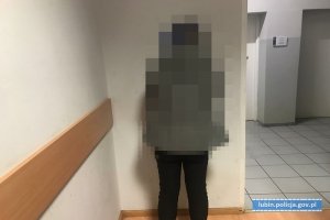 Zatrzymana przez policjantów kobieta stoi pod ścianą