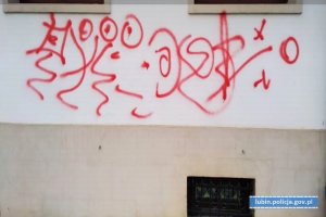 Ściana elewacyjna budynku ratusza. Pod oknami narysowane graffiti składające się z nic nie znaczących znaków koloru czerwonego.