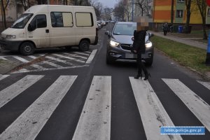 Piesza na przejściu dla pieszych. Przepuszczające ją auto stoi przed pasami