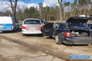 Radiowóz policyjny i auto sprawców i pokrzywdzonego na parkingu, gdzie doszło do kradzieży