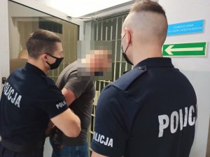 Policjanci przed pomieszczeniem dla osób zatrzymanych z podejrzanym mężczyzną