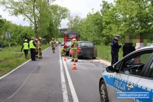 Radiowóz na miejscu zdarzenia, policjanci, strażacy, uszkodzone pojazdy