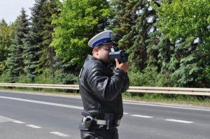 Policjant ruchu drogowego na poboczu drogi sprawdza prędkość kierujących