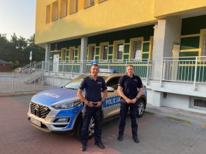 Dwóch policjantów stoi przy radiowozie