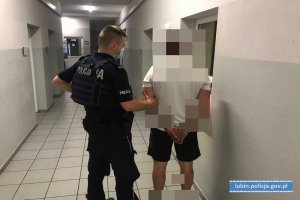 Policjant stoi z zatrzymanym mężczyzną